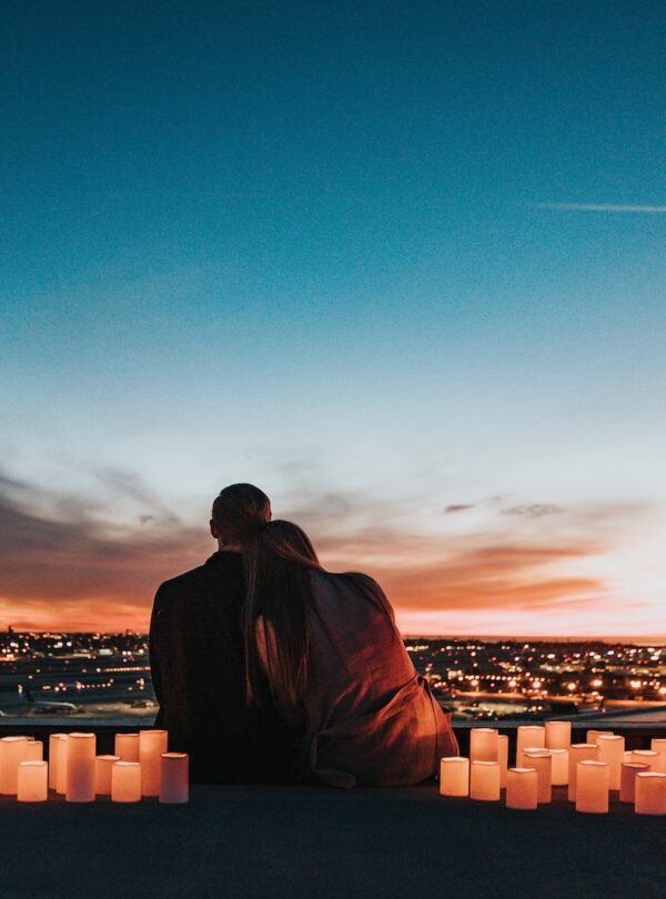 romantic couple sitting on the field facing the city