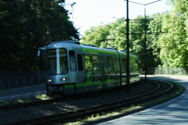 a green and white train traveling down train tracks