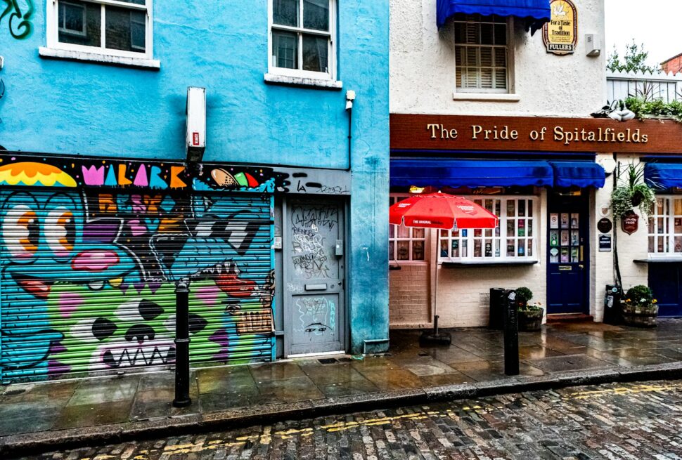 people walking on sidewalk near blue and green concrete building during daytime